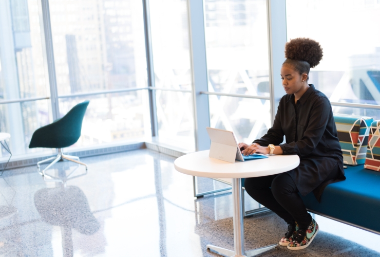 woman sitting at table with laptop in front of windows